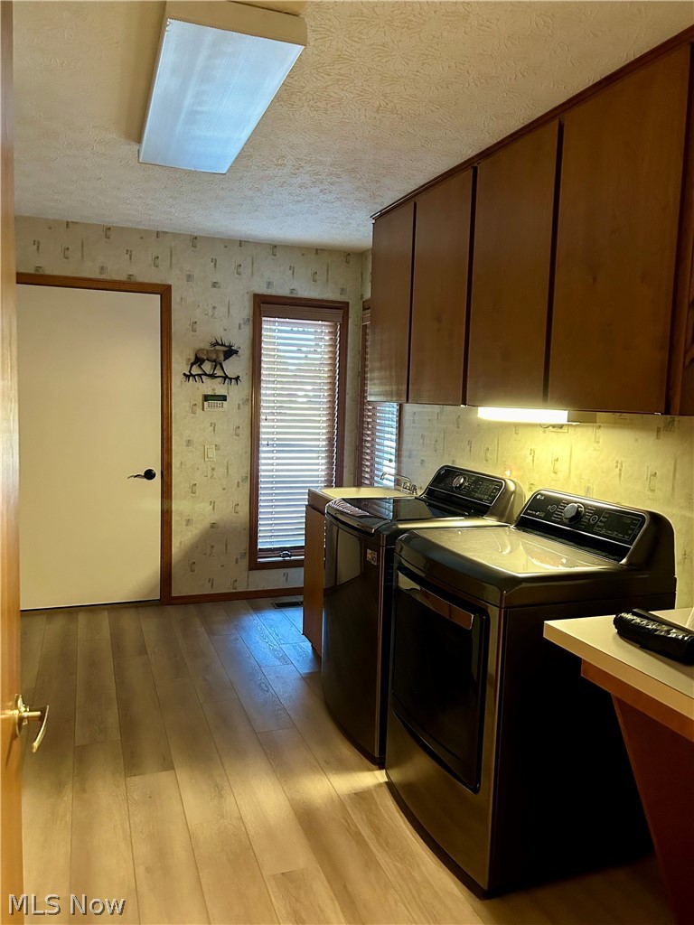 8763 Timber Edge Drive North Ridgeville, OH 44039 - Photo 29 of 40 Kitchen with dark brown cabinets, washing machine and clothes dryer, a textured ceiling, and light hardwood / wood-style flooring