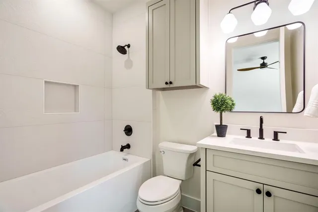 a bathroom with a toilet a sink a mirror a bathtub and vanity