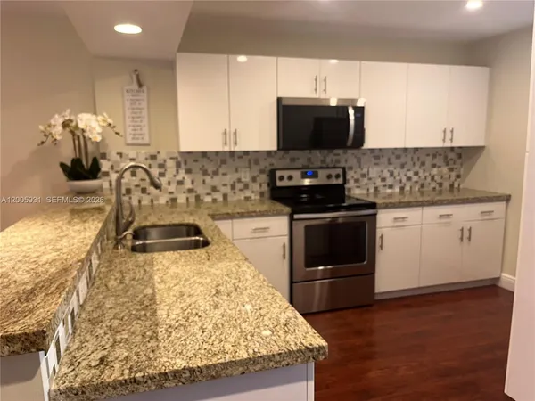 a kitchen with stainless steel appliances granite countertop a stove a sink and a microwave