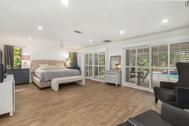 a spacious bedroom with a bed a table and wooden floor