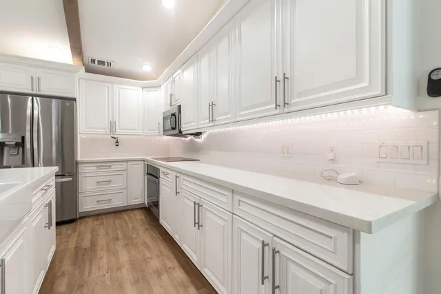 a kitchen with white cabinets sink and stainless steel appliances