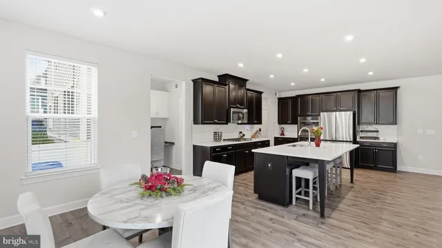 a kitchen with stainless steel appliances kitchen island granite countertop a dining table chairs and granite counter tops