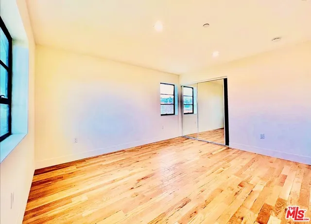 a view of empty room with wooden floor and fan