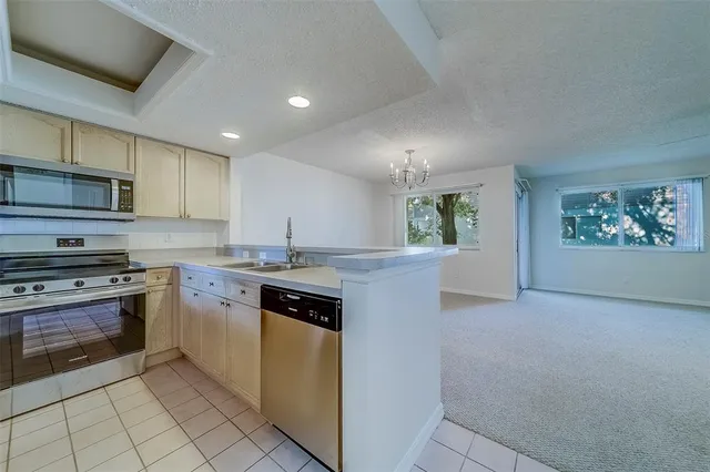a view of a room with a chandelier fan and kitchen view