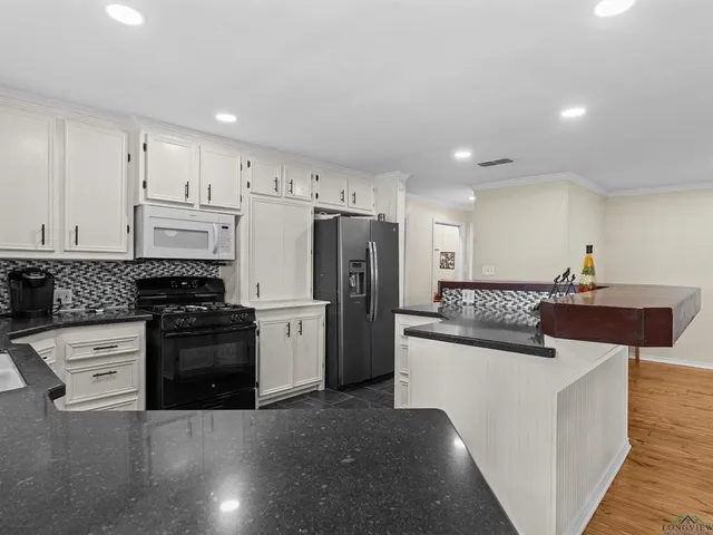 a kitchen with stainless steel appliances kitchen island granite countertop a refrigerator and a stove top oven