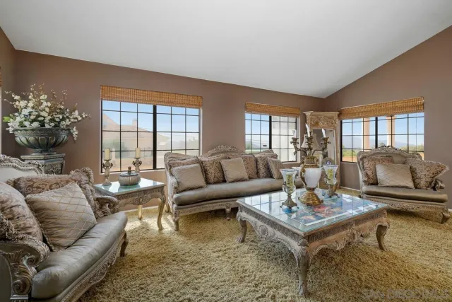 a living room with furniture a fireplace and large windows