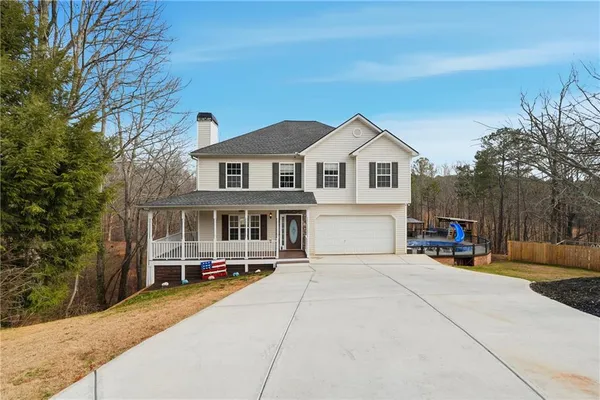 a view of a house with a small yard and large trees