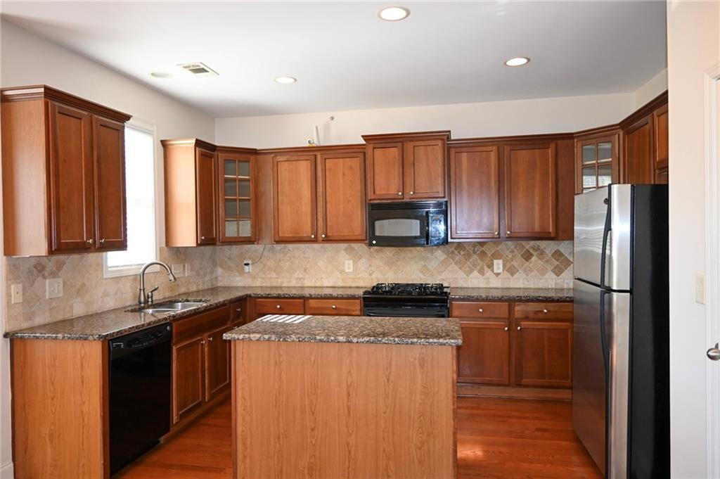 25 Kaktovic Court Southeast Grayson, GA 30017 - Photo 16 of 56 a kitchen with stainless steel appliances granite countertop a stove a sink dishwasher a refrigerator and cabinets with wooden floor