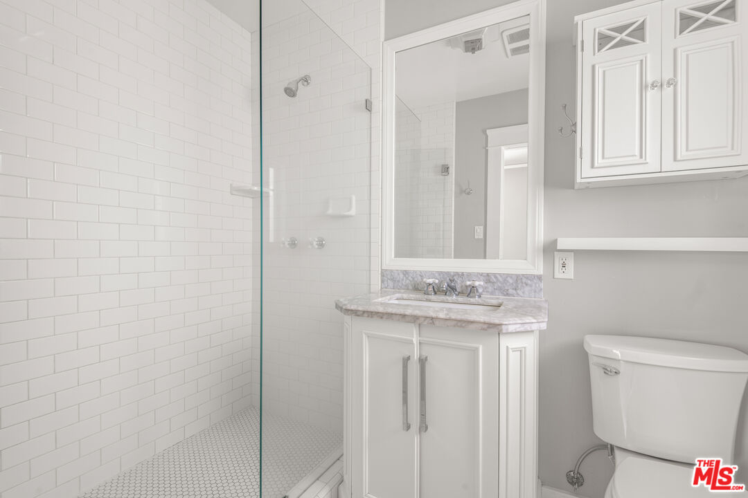 1047 9th Street Santa Monica, CA 90403 - Photo 7 of 20 a bathroom with a granite countertop toilet a sink and a mirror