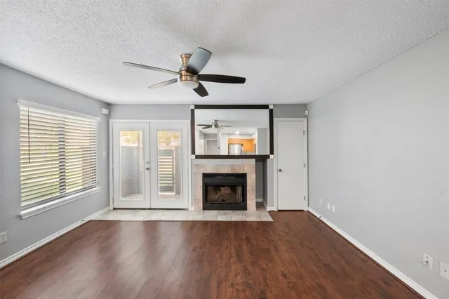 a view of an empty room with wooden floor fireplace and a window