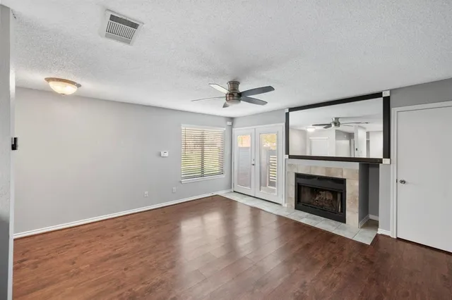 a view of an empty room with wooden floor fireplace and a window