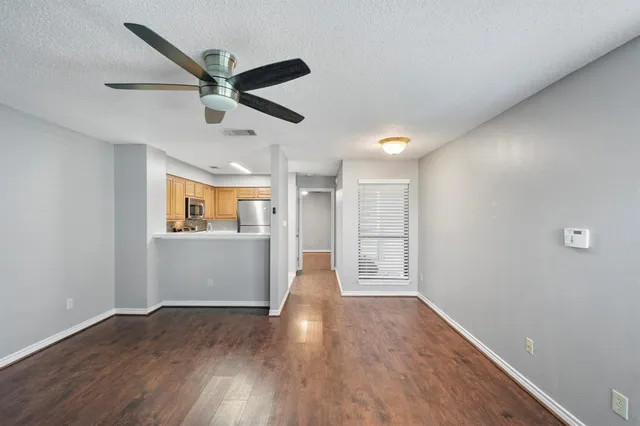 a view of empty room with wooden floor and ceiling fan