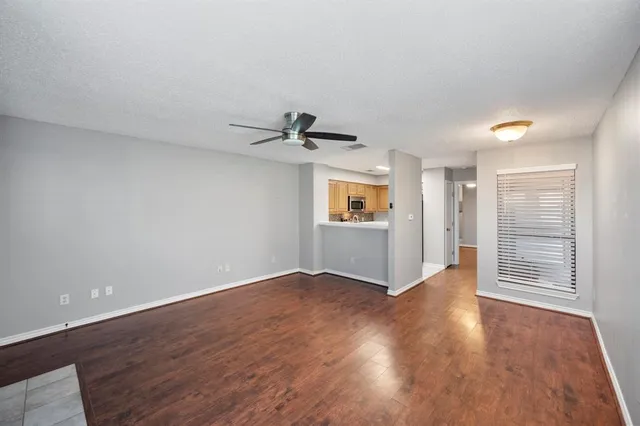 an empty room with wooden floor cabinet and windows