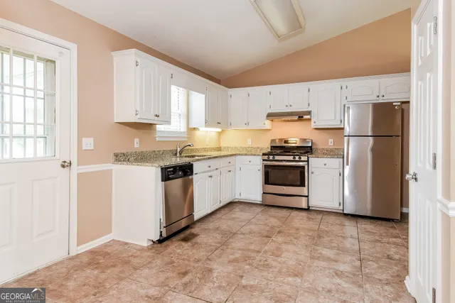 a kitchen with granite countertop white cabinets and refrigerator
