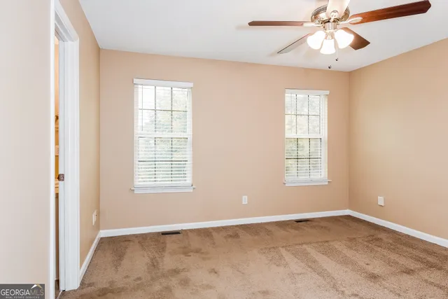 an empty room with chandelier fan and windows