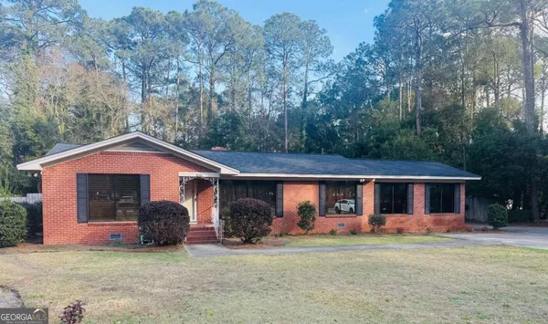 a front view of a house with a garden and trees