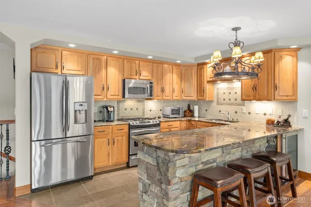 a kitchen with stainless steel appliances granite countertop a refrigerator a stove a sink dishwasher and a refrigerator with wooden cabinets