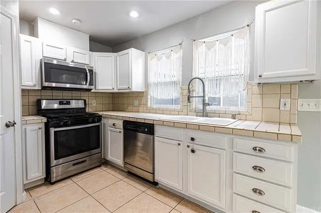 a kitchen with stainless steel appliances granite countertop white cabinets a sink and a stove