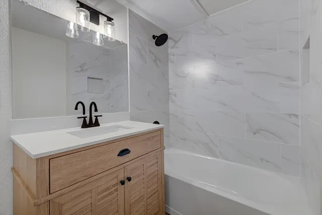 a bathroom with a bathtub sink vanity and mirror
