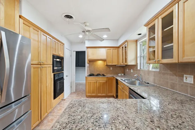 a kitchen with stainless steel appliances granite countertop a refrigerator a stove and a sink with wooden floor