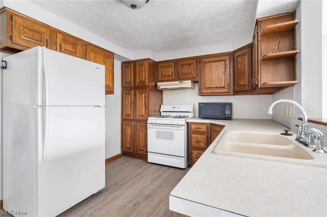 2942 17th Street Northwest Canton, OH 44708 - Photo 9 of 25 Kitchen featuring white appliances, a textured ceiling, light hardwood / wood-style floors, and sink