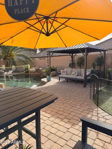 a backyard of a house with table and chairs under an umbrella