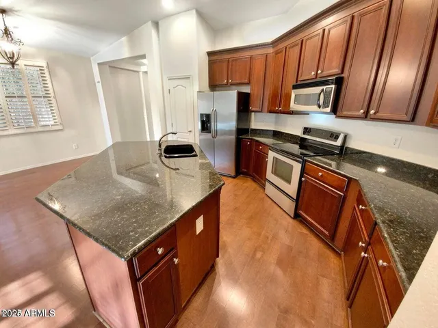 a kitchen with stainless steel appliances granite countertop a sink stove microwave and refrigerator