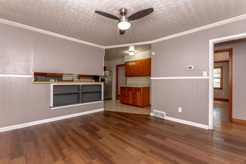 5595 Raleigh Lagrange Road Memphis, TN 38134 - Photo 14 of 29 an empty room with wooden floor a ceiling fan and a kitchen space