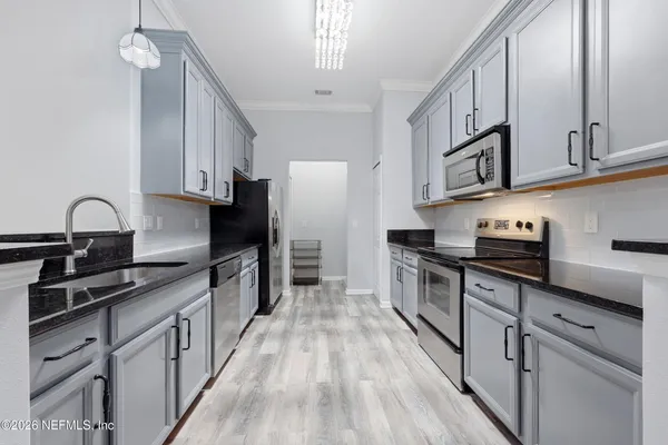 a kitchen with stainless steel appliances granite countertop a stove top oven a sink dishwasher and a refrigerator with wooden cabinets