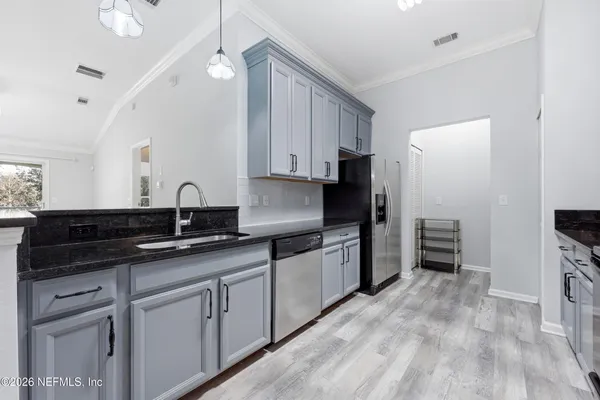 a kitchen with granite countertop a sink cabinets stainless steel appliances and a window