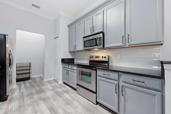 a kitchen with stainless steel appliances granite countertop white cabinets and a stove top oven