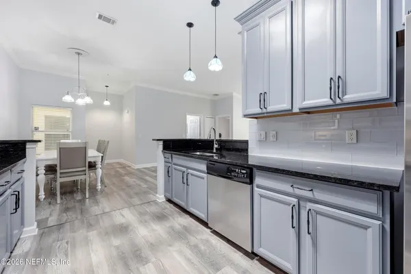 a kitchen with granite countertop a sink a counter space appliances and cabinets