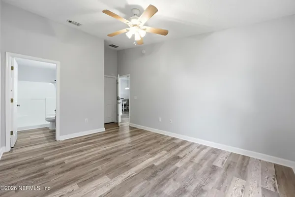 an empty room with wooden floor and ceiling fan