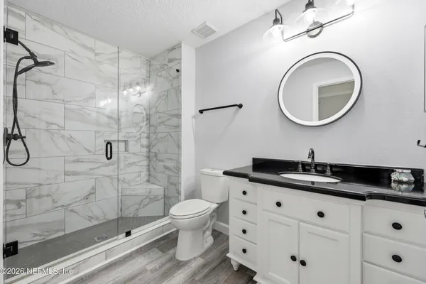 a bathroom with a granite countertop sink toilet and shower