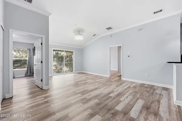 a view of an empty room with wooden floor and a window