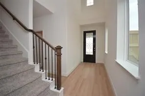 a view of a hallway with wooden floor and stairs