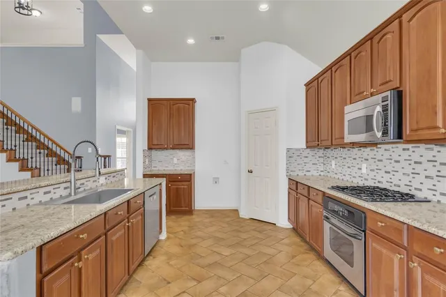 a large kitchen with stainless steel appliances granite countertop a sink stove and cabinets