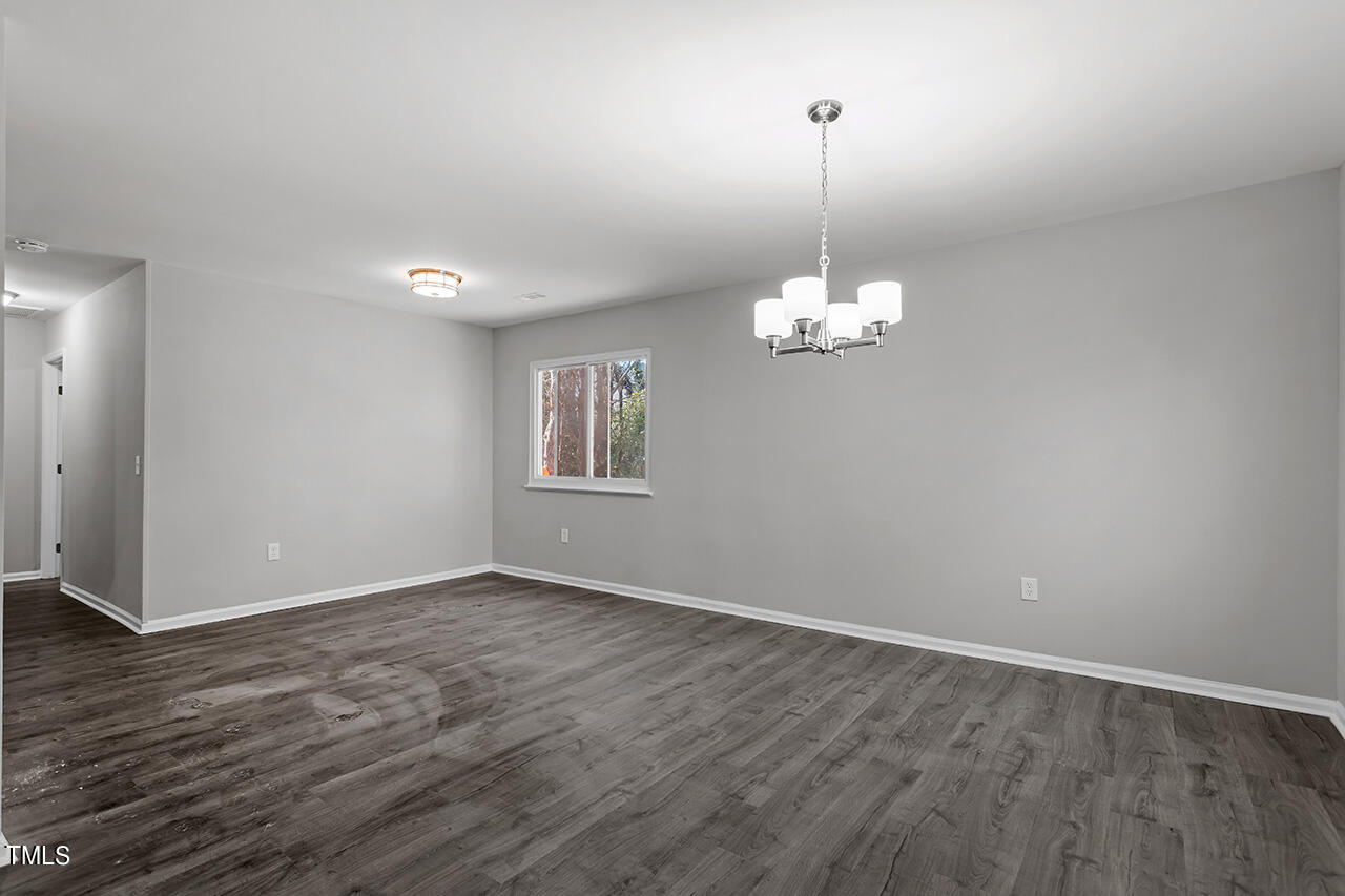 1209 Hazelnut Drive Raleigh, NC 27610 - Photo 11 of 24 an empty room with wooden floor chandelier and windows