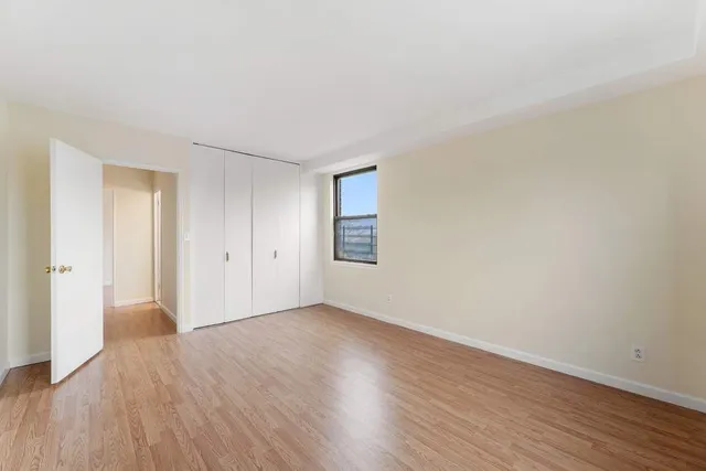 a view of an empty room with wooden floor and windows