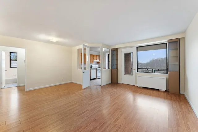 a view of an empty room with window and wooden floor