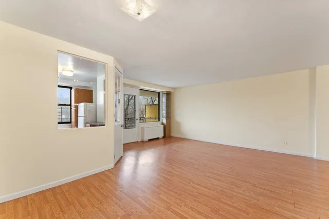 an empty room with wooden floor and mirror