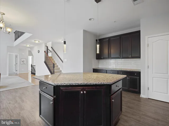 a kitchen with stainless steel appliances granite countertop a sink dishwasher a stove and a refrigerator with wooden floor