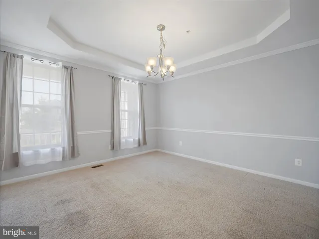 an empty room with chandelier and windows
