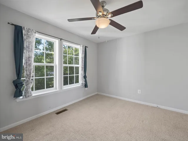 en empty room with windows and ceiling fan