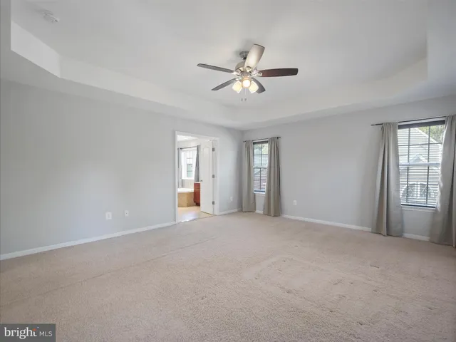 a view of an empty room with chandelier fan and a window