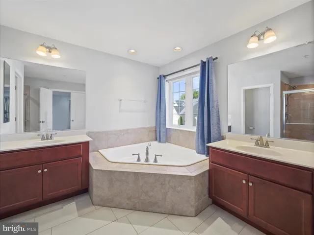 a bathroom with a tub a sink double vanity granite and tub