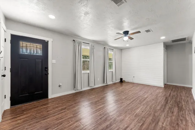 an empty room with wooden floor and ceiling fan