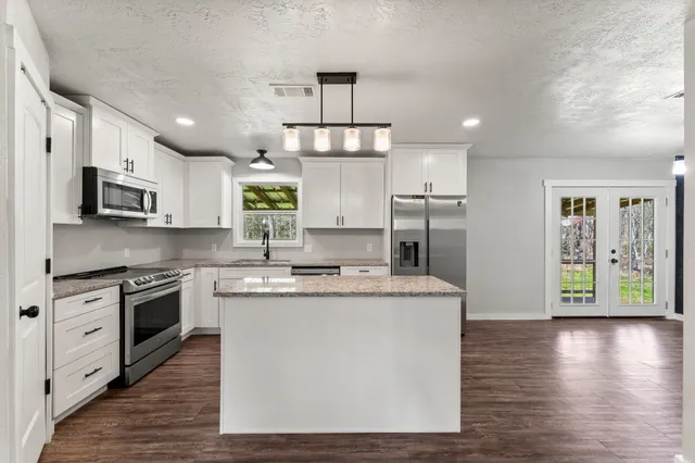a kitchen with stainless steel appliances granite countertop wooden floor sink stove and wooden cabinets