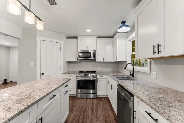 a kitchen with stainless steel appliances granite countertop a sink stove and refrigerator