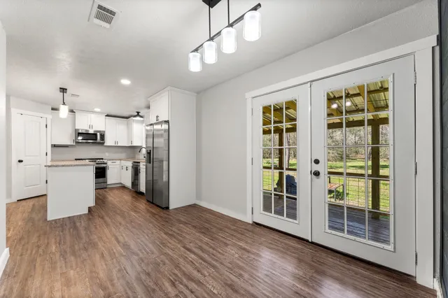 a kitchen with stainless steel appliances granite countertop a refrigerator a stove a sink dishwasher a oven with white cabinets and wooden floor